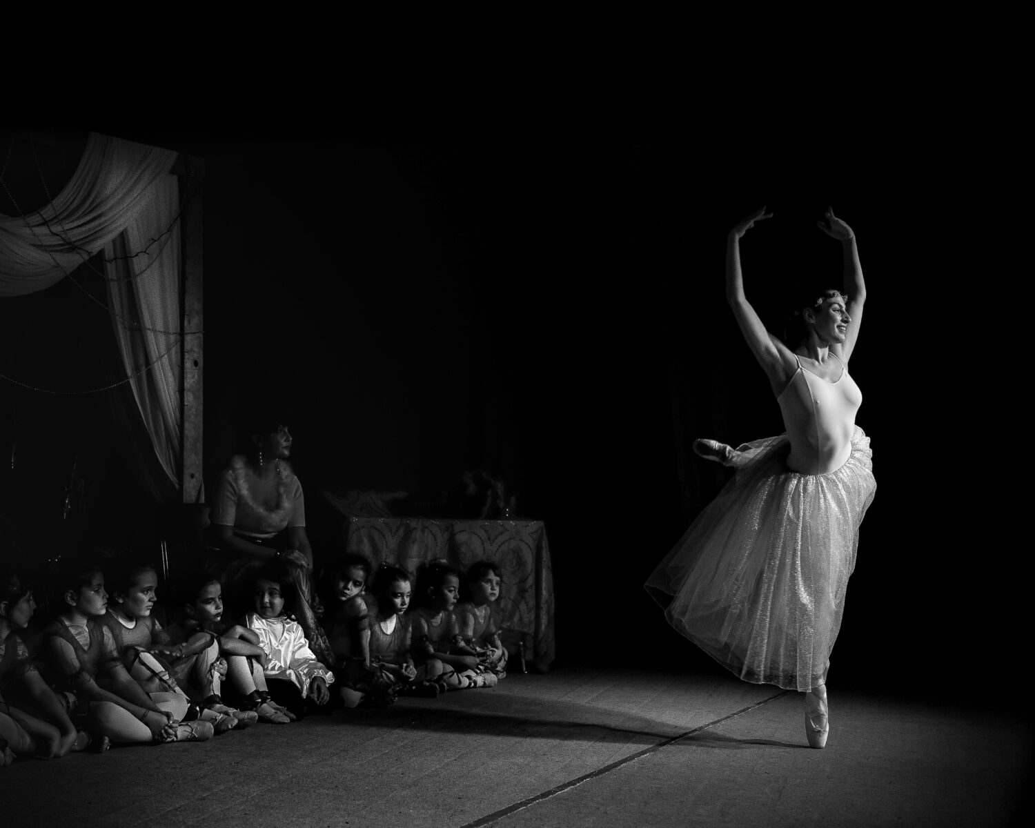 La levità dei gesti di una ballerina di danza classica incantano il gruppo
delle bambine di una scuola di ballo, pronte con le loro scarpine a
cimentarsi in faticosi esercizi: ma il sogno esiste e potrebbe diventare
realtà.
(Maria Antonietta Spadaro)